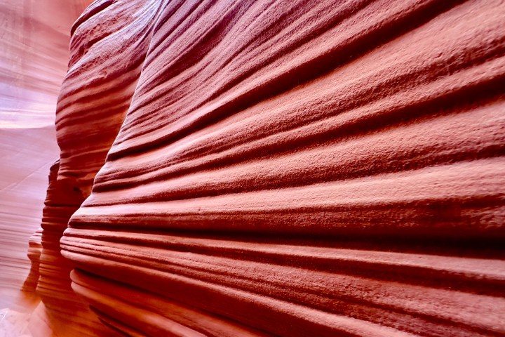 Close-up of textured red sandstone canyon walls with layered patterns.