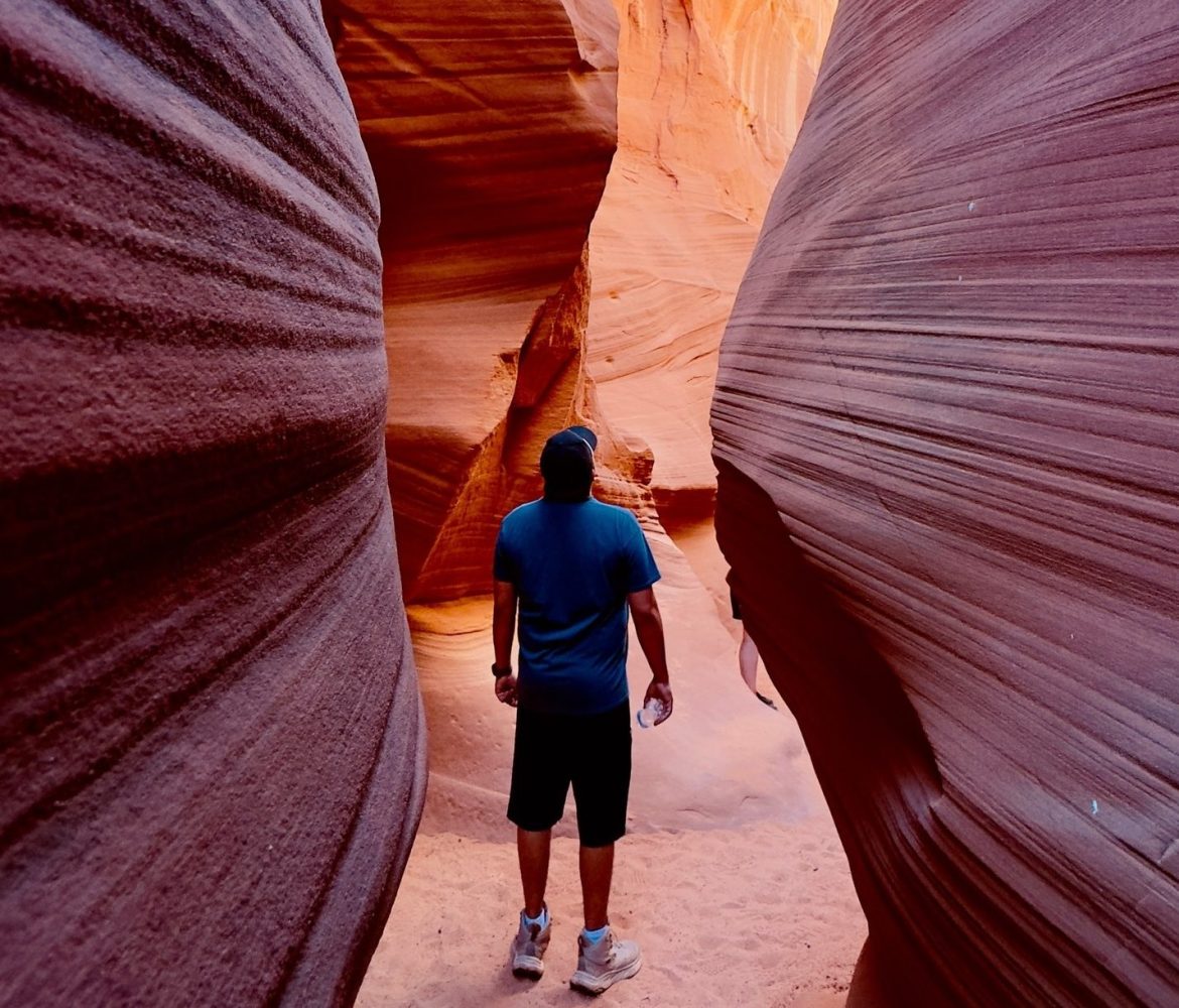 Person standing between narrow, textured canyon walls.